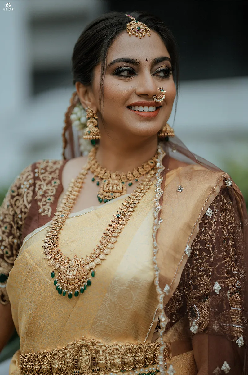 Bride with intricate gold jewelry and a golden saree.