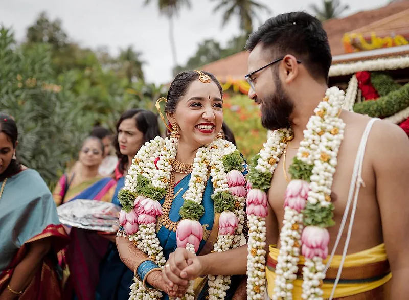 Radiant Blue Saree Muhurtham Bride - Dejavu Makeup Studio Bangalore bride in blue saree with bridal makeup and floral garlands, smiling., soft-glam finish